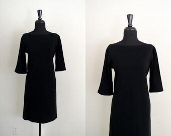 May include: A black, short-sleeved dress with a boat neck.