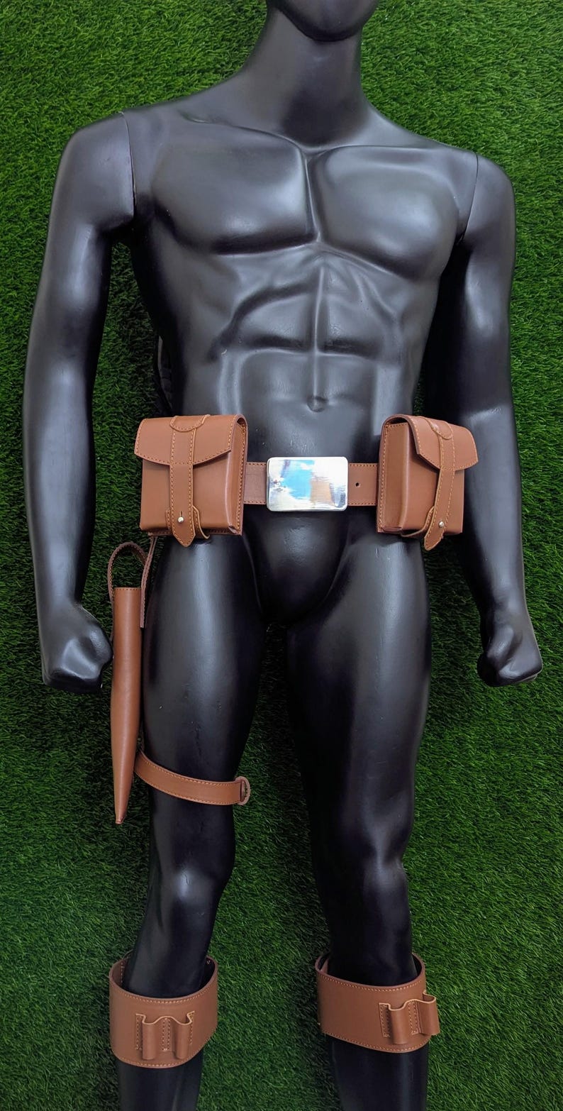 Puede incluir: Un cintur&oacute;n de cuero marr&oacute;n con dos bolsas a cada lado y una hebilla plateada. El cintur&oacute;n se lleva en un maniqu&iacute; con correas de pierna de cuero marr&oacute;n y bolsas.