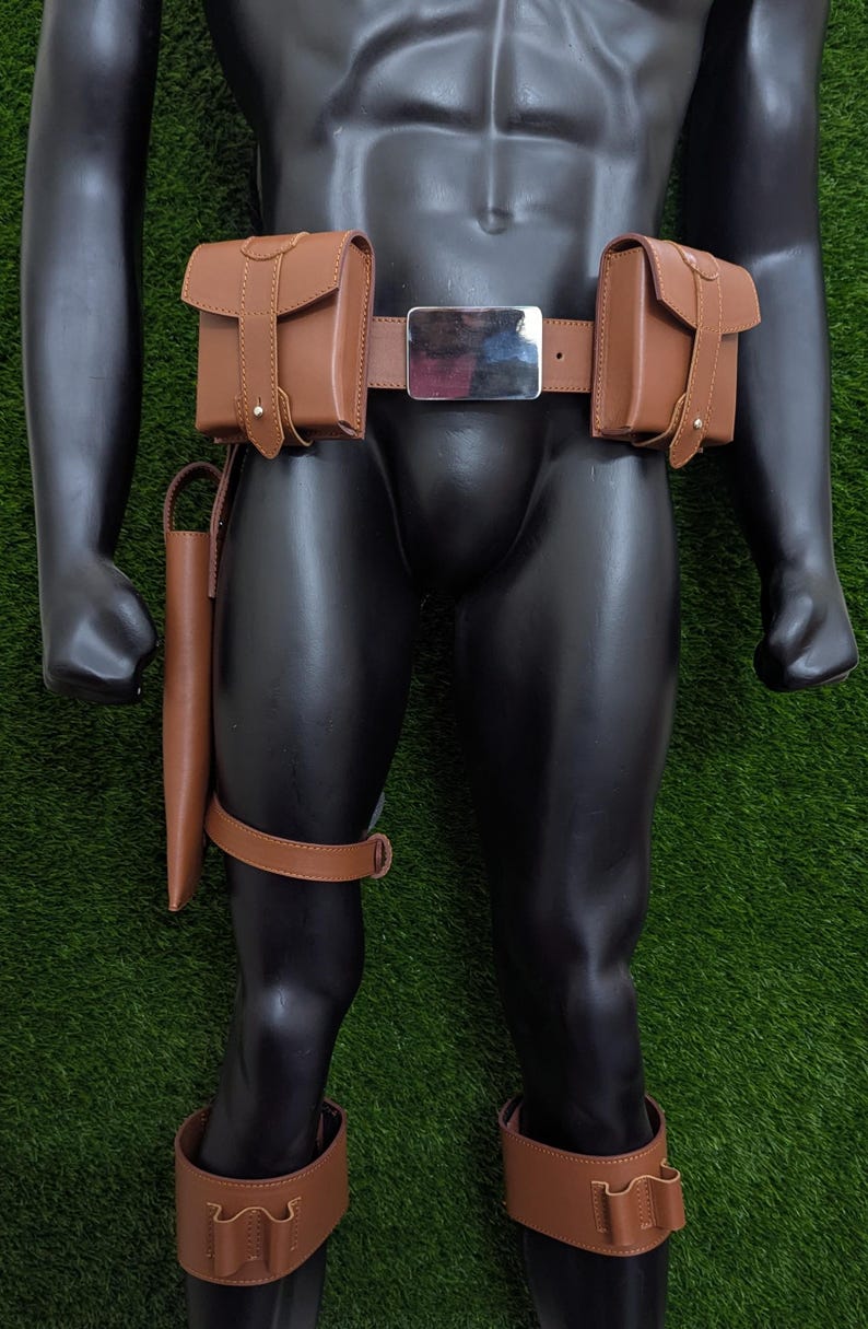 Puede incluir: Un cintur&oacute;n de cuero marr&oacute;n con dos bolsas a cada lado y una hebilla plateada. El cintur&oacute;n se lleva en un maniqu&iacute; con correas de pierna de cuero marr&oacute;n y bolsas.