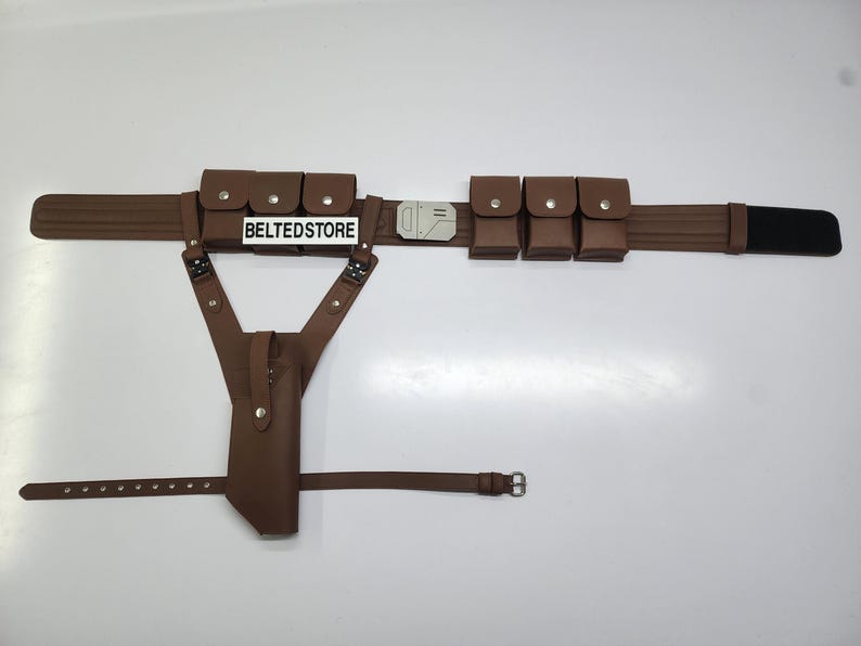 May include: A brown utility belt with multiple pouches and a holster. The belt features a rectangular buckle and a black section at the end. The text "BELTEDSTORE" is visible on a white label.