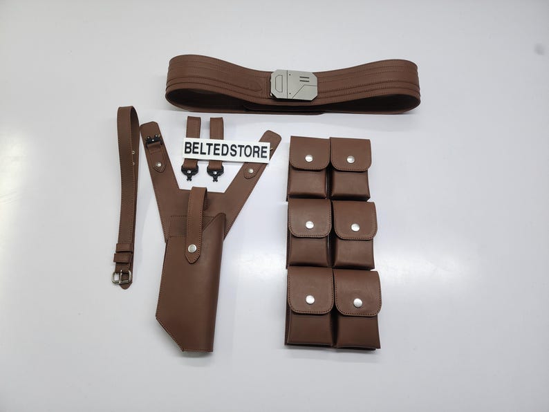 May include: A brown leather belt with a silver buckle, a holster, a shoulder strap, and multiple pouches. The text "BELTEDSTORE" is visible on a white sign.