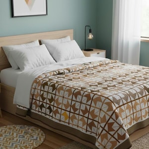 Puede incluir: Una cama con ropa de cama blanca y un edredón con estampado geométrico en tonos marrones, beige y blanco. El edredón tiene un borde marrón oscuro. Una alfombra redonda con un patrón similar está en el suelo.