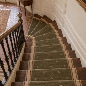 May include: A staircase with dark wood treads and a central green runner rug featuring a repeating small white floral pattern and beige borders. A dark wood banister with vertical spindles runs along the left side of the descending stairs.