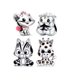 Op de afbeelding: Vier zilveren dierenbedels: een kat met een roze strik en hart, een hamster, een zebra en een giraffe met bruine vlekken. Deze bedels zijn waarschijnlijk voor een armband of ketting.