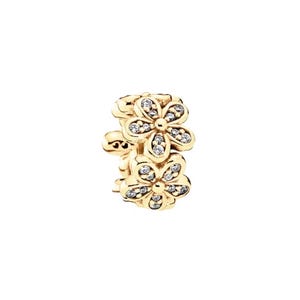 May include: A gold-colored charm featuring two stacked flower designs. Each flower has five petals and is embellished with small, clear gemstones. The charm is designed for jewelry and has a clasp.