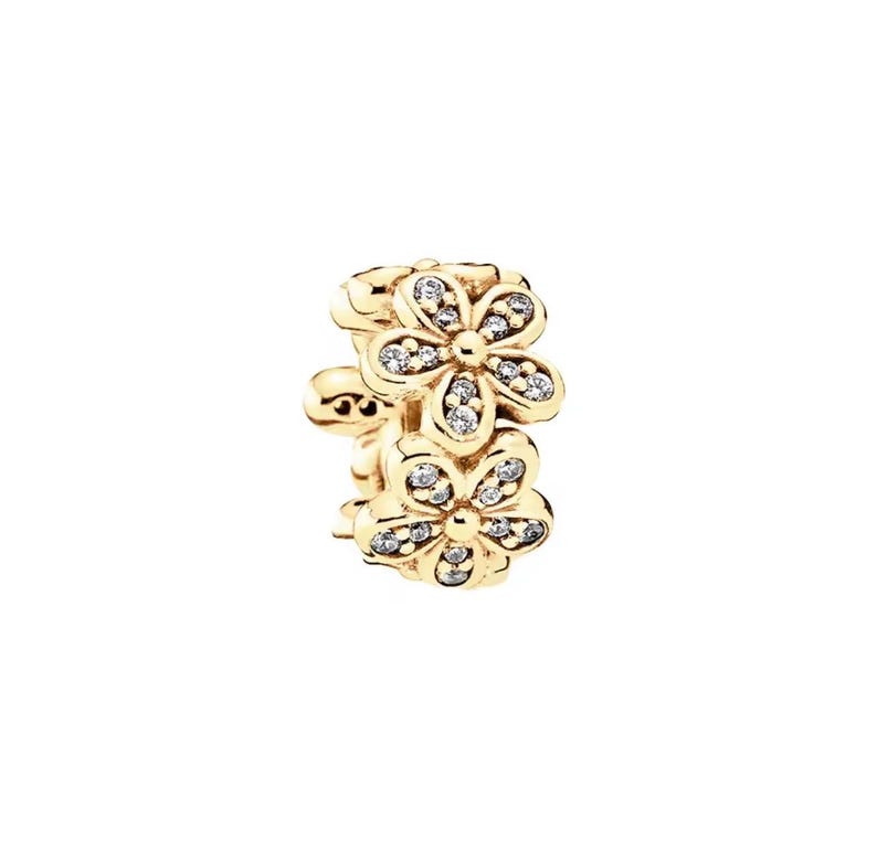 May include: A gold-colored charm featuring two stacked flower designs. Each flower has five petals and is embellished with small, clear gemstones. The charm is designed for jewelry and has a clasp.