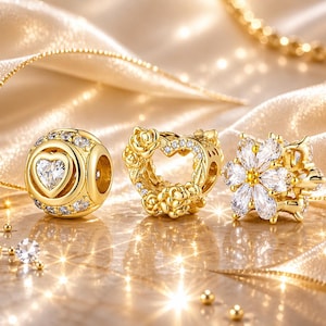 May include: Three gold-colored charm beads. One is a sphere with a heart-shaped crystal, surrounded by smaller crystals. Another is a heart-shaped charm with rose details and crystals. The third is a flower-shaped charm with white crystals.