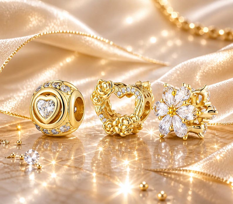 May include: Three gold-colored charm beads. One is a sphere with a heart-shaped crystal, surrounded by smaller crystals. Another is a heart-shaped charm with rose details and crystals. The third is a flower-shaped charm with white crystals.