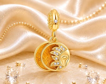 May include: A gold-toned charm pendant featuring a circular design with a textured sun and moon motif. The sun portion is accented with small clear stones, and the bail is decorated with a single stone. The charm hangs from a delicate gold chain.