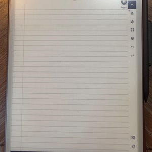 May include: A digital notepad with a lined page displayed. The screen shows the text "page 3 of 522" and "Back to page 2". A stylus is attached to the side. The notepad has a dark border and is on a wooden surface.