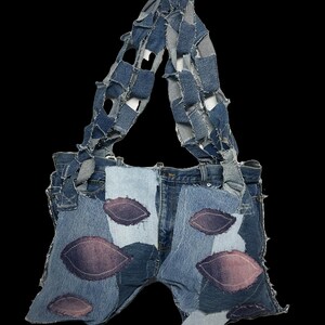 May include: A pair of denim dungarees with a patchwork design. The dungarees are made of different shades of blue denim and have been patched together with various pieces of fabric. The straps of the dungarees are made of a single piece of denim that has been cut into strips and then sewn together.