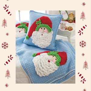 May include: A light blue crocheted pillow and blanket set featuring Santa Claus faces. The Santa faces have red hats, green trim, pink cheeks, and white beards. The blanket and pillow are decorated with a Christmas theme.