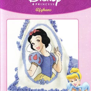 Pode incluir: Um livro de padrões de crochê com três desenhos para afegãos da Disney Princess. A capa mostra um afegão da Branca de Neve acabado com uma borda azul. O logotipo da Disney Princess está no topo.