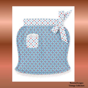 May include: A blue apron with a floral pattern, a pocket, and a white lace trim. The apron has a bow at the top and a pocket with a floral design. The apron is from the Vintage Collection.