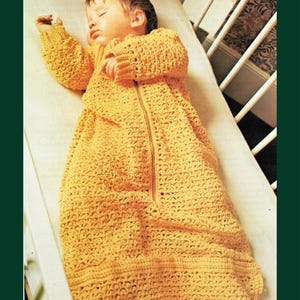 May include: A baby asleep in a yellow crocheted sleep sack with long sleeves and a front zip. The sleep sack is made of textured yarn and is on a white sheet in a cot. The image is from the Beecra Vintage Collection.