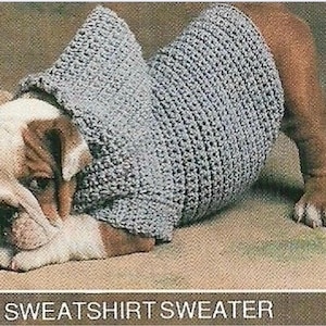 May include: A light gray crocheted dog sweater with a hood, worn by a bulldog. The dog is lying down, with its head resting on its paws. The text "SWEATSHIRT SWEATER" is at the bottom of the image.