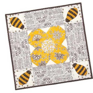 Puede incluir: Un bloque de colcha de tela floral amarillo y blanco con un diseño de abeja. El bloque está rodeado de una tela blanca con texto negro que dice "Bee Positive", "Bee Respectful", "Bee Grateful", "Hive Rules", y más.