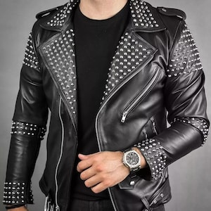 May include: A black leather jacket with silver studs on the collar, shoulders, and sleeves. The jacket has a zipper closure and a belt at the waist.