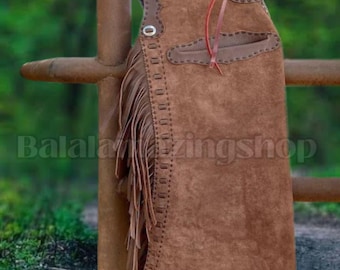 May include: Brown suede chaps with fringe detail and decorative stitching. The chaps are hanging on a brown metal fence. The text "Balala Amazing Shop" is visible on the chaps.