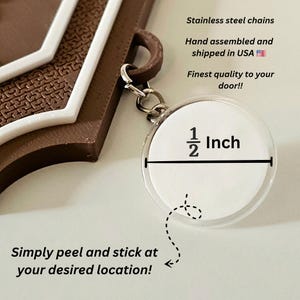 May include: A keychain with a clear, circular charm, measuring 0.5 inches in diameter, attached to a brown and white decorative piece. The text on the charm reads "1/2 Inch". The image also includes the text "Simply peel and stick at your desired location!"