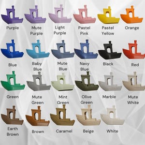 May include: A collection of small, boat-shaped decorative objects in various colors, including purple, blue, green, and brown. Each boat has a cabin and a chimney, with color names labeled below.