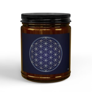 May include: A brown glass jar with a black lid. The jar has a dark blue label with a white and light blue geometric flower of life design. The jar is filled with a light brown substance.