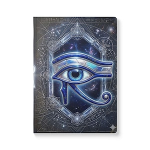 May include: A notebook featuring a detailed illustration of the Eye of Horus, rendered in shades of blue and silver against a cosmic background. The cover design includes geometric shapes and ancient Egyptian symbols, creating a mystical aesthetic.
