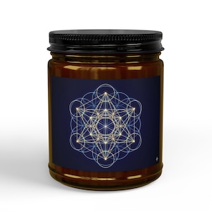 May include: A glass jar with a black lid, filled with a light-colored substance. The jar has a dark blue label with a geometric design in white and gold. The design features intersecting circles and lines.