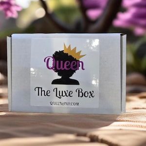 Puede incluir: Caja blanca con una pegatina que dice "Queen The Luxe Box QUEENANP.COM". La pegatina presenta una silueta negra de una mujer con una corona en la cabeza.