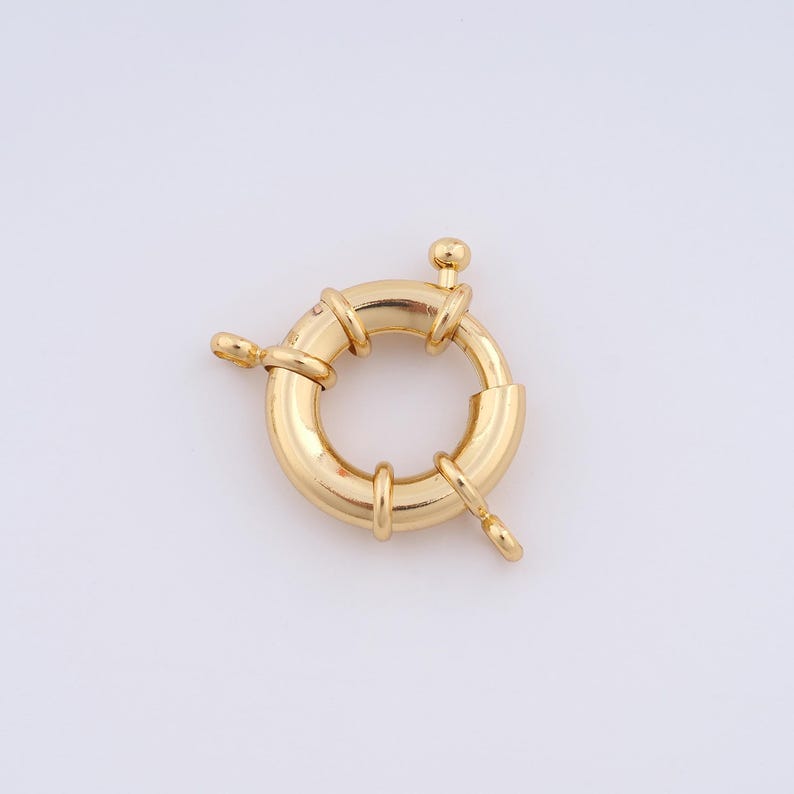 May include: Gold-toned metal clasp with a round ring and three prongs. The clasp is designed to be used for necklaces, bracelets, or other jewelry.