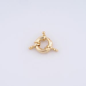 May include: Gold-toned metal clasp with a round ring and three loops. The clasp is designed to connect two pieces of jewelry.