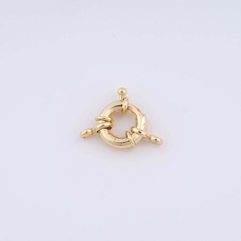May include: Gold-toned metal clasp with a round ring and three loops. The clasp is designed to connect two pieces of jewelry.