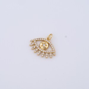 May include: Gold eye charm with a star in the center, surrounded by clear cubic zirconia stones.