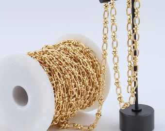 May include: A spool of gold-colored chain with a length of chain hanging from the spool. The chain is made of small, oval-shaped links.