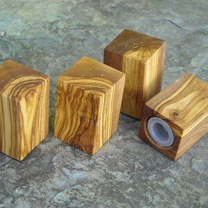 May include: Four wooden salt and pepper shakers made from olive wood. The shakers are square and have a natural wood finish.