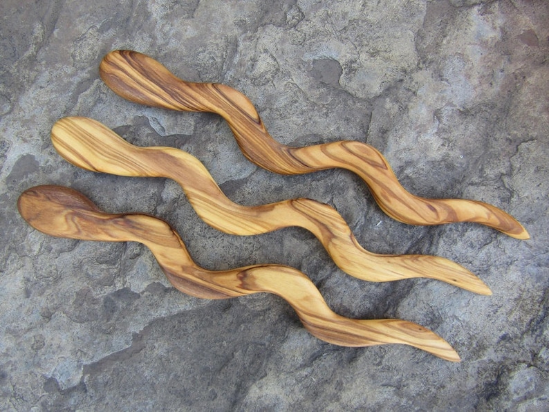 Puede incluir: Tres palos de pelo de madera con un dise&ntilde;o ondulado. Los palos son de madera de olivo y tienen un color marr&oacute;n natural.
