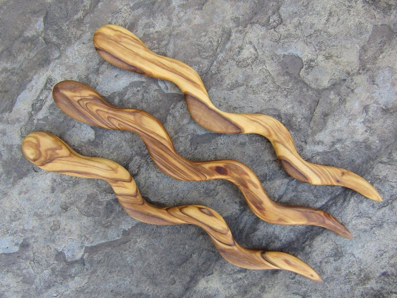 Puede incluir: Tres peines de madera para el cabello con un dise&ntilde;o ondulado y serpentino. Los peines est&aacute;n hechos de madera de olivo y tienen un color marr&oacute;n claro natural.