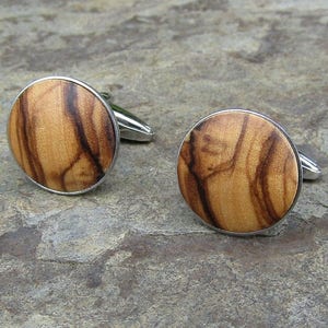 May include: A pair of cufflinks with a round, wooden design. The wood is a light brown colour with dark brown streaks. The cufflinks are made of silver metal.