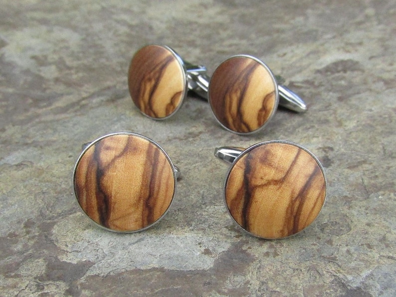 May include: Four silver cufflinks with round wooden inlays. The wood has a natural brown and dark brown grain pattern.