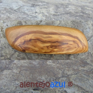 Pode incluir: Um close-up de uma travessa de servir de madeira de oliveira. A travessa é de cor marrom claro com padrões de grão marrom escuro. A travessa tem a forma de um barco.