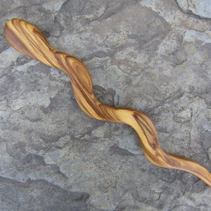 Puede incluir: Un palo de pelo de madera con un acabado de madera natural y una forma ondulada y serpentina.