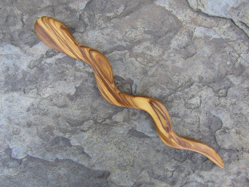 Puede incluir: Un palo de pelo de madera con un acabado de madera natural y una forma ondulada y serpentina.