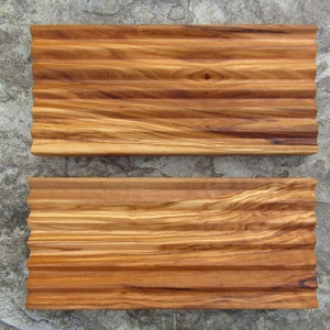 Puede incluir: Dos bandejas de servir de madera con un dise&ntilde;o ondulado y acanalado. Las bandejas son de madera marr&oacute;n claro con vetas marr&oacute;n oscuro.