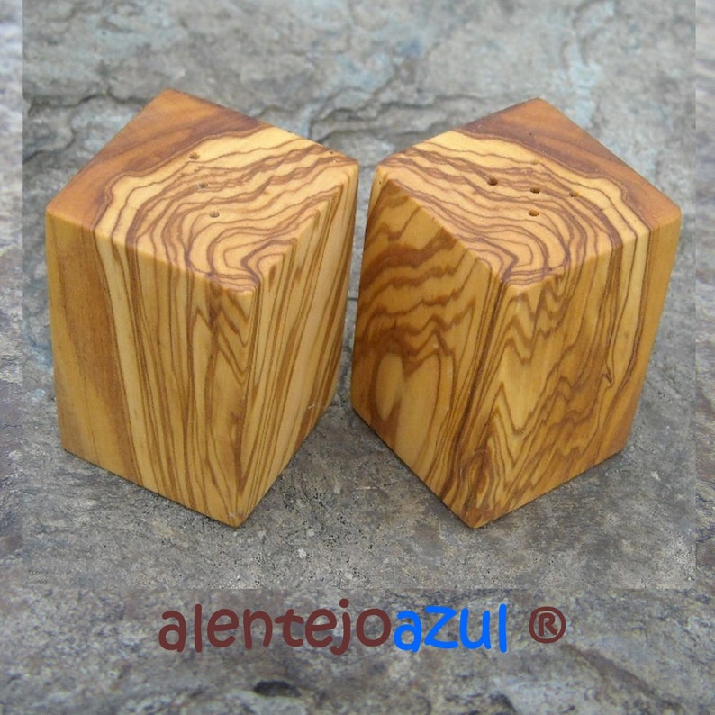 May include: Two square wooden salt and pepper shakers made of olive wood with a natural wood grain pattern.
