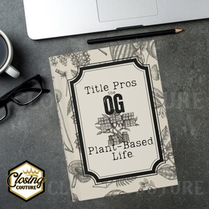 May include: A book titled "Title Pros the OG Plant-Based Life" with a black and white design. The book is on a gray surface with a laptop, pencil, glasses, and a cup of coffee. The book cover has a decorative border and botanical illustrations.