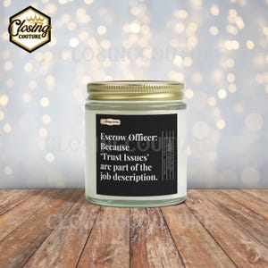 May include: A clear glass candle jar with a gold lid. The label reads "Escrow Officer: Because 'Trust Issues' are part of the job description." The Closing Couture logo is in the upper left corner. The candle sits on a wooden surface.