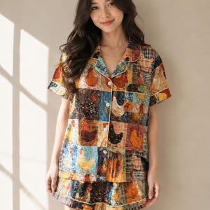 May include: A short-sleeved button-down pajama shirt and matching shorts set featuring a patchwork design of various chickens in shades of orange, brown, black, blue, and white. The garment has a notched collar, white buttons, and white piping.