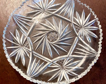 May include: A clear glass serving dish with a starburst pattern. The dish has a scalloped edge and is perfect for serving snacks or desserts.