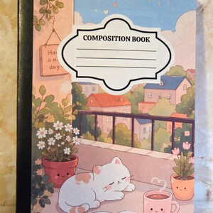 May include: A composition book featuring a cover illustration of a white cat sleeping on a balcony with potted flowers and a pink mug. The background shows a townscape under a sunlit sky. A white label with the text COMPOSITION BOOK is centred.