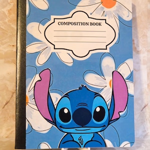 May include: A composition book with a blue cover featuring a repeating white daisy pattern with orange centres. The character Stitch is printed at the bottom with large purple ears. A white label with the text COMPOSITION BOOK is centred.